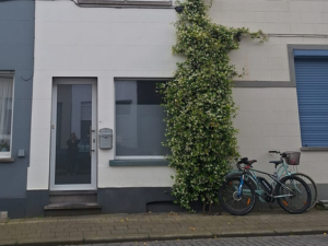 Vooraanzicht van het filiaal van Hypnosecentrum.be in Kortrijk, een knus en modern pand met groene klimop en een fiets voor de deur.