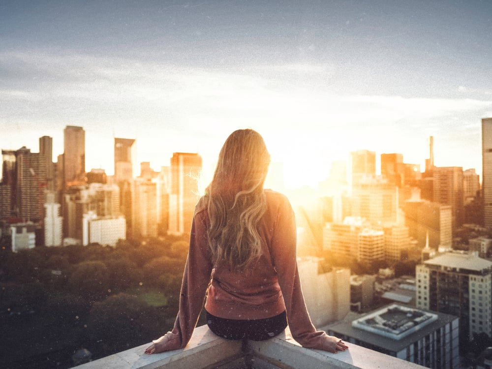 Hoogtevrees overwinnen met Hypnotherapie 2 Een vrouw kijkt vanaf een hoog gebouw uit over de stad.