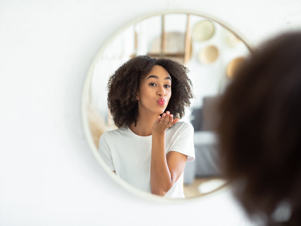 Zelfbeeld versterken met Hypnotherapie 2 Een vrouw blaast een kus naar haar spiegelbeeld.